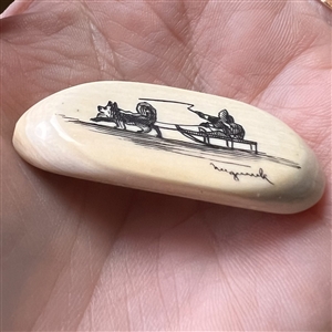 Scrimshaw button of an Eskimo riding in a dogsled on natural material.