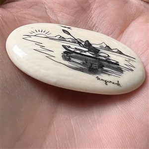 Scrimshaw button of an Eskimo paddling a kayak on natural material.