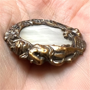 Shell set in brass button with elaborate pictorial border.