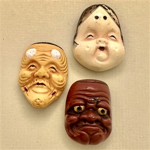 Three ceramic Asian mask netsukes.