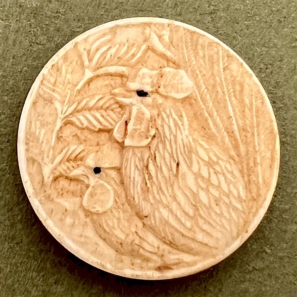 Carved natural material button of two chickens.