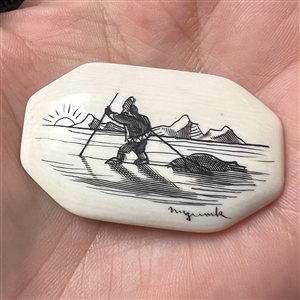 Scrimshaw button of an Eskimo hunting on natural material.