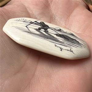 Scrimshaw button of an Eskimo hunting on natural material.