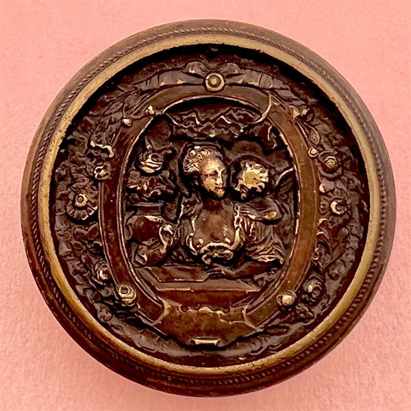 Stamped brass button of woman interacting with a cherub.