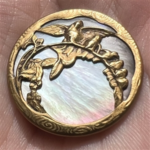 Iridescent shell button with birds on a branch.