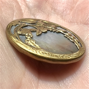 Iridescent shell button with birds on a branch.