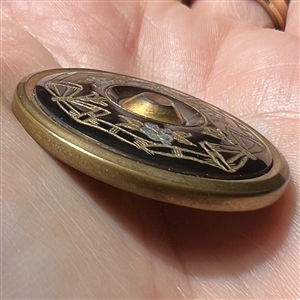 Iridescent brown pearl button with incised design.