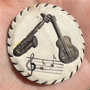 Vintage white leather button with musical instruments.