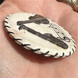 Vintage white leather button with musical instruments.