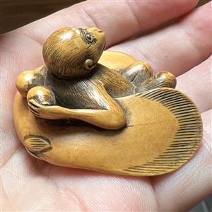 Monkey holding a fish netsuke.