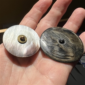 Two smoky pearl buttons of heads.