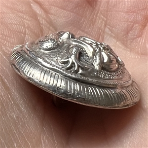 Highly sculptural silver button of a dragon.