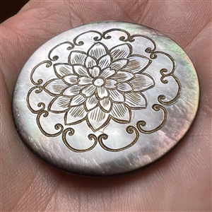 Grey pearl button with incised design of flower.