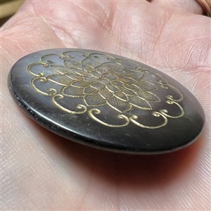 Grey pearl button with incised design of flower.