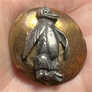 Brass and white metal penguin button.