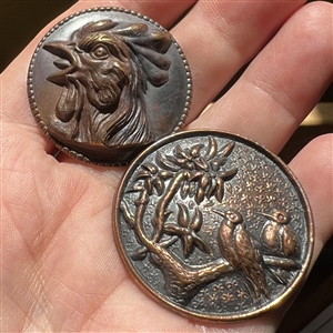 Two metal buttons of birds.