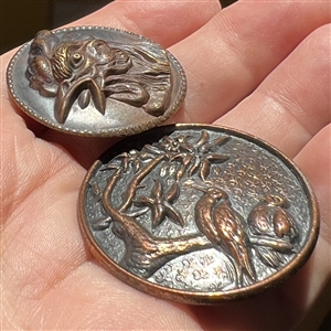 Two metal buttons of birds.