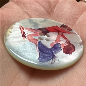 Transfer on iridescent shell button of two children on a swing.
