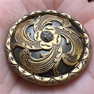 Brass openwork metal over darkened metal button.