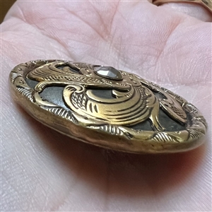 Brass openwork metal over darkened metal button.