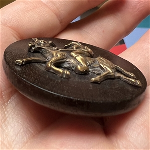 Wood button of Punchinello riding a donkey.