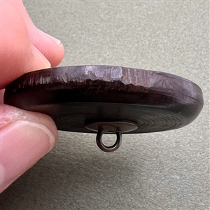 Wood button of Punchinello riding a donkey.
