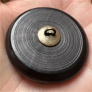 Wood button of Punchinello riding a donkey.