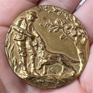 Stamped brass button of a hunter and his dog. 
