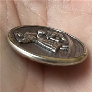 Stamped white metal button of a woman standing in a boat with a man.