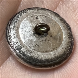 Stamped white metal button of a woman standing in a boat with a man.