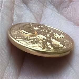 Stamped yellow metal button of a gnome with a toadstool as umbrella.