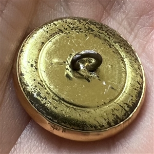 Stamped yellow metal button of a gnome with a toadstool as umbrella.