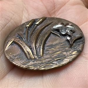 Stamped brass button of cattails and a flower.