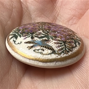 Satsuma button of a bird flying under Wisteria.