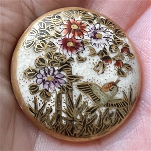 Satsuma button of a bird flying over flowers.