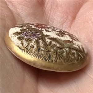 Satsuma button of a bird flying over flowers.