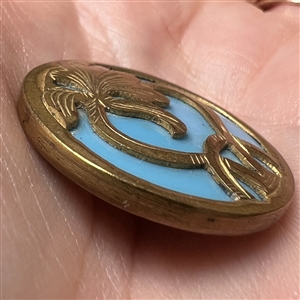 Turquoise glass set in brass button of an Art Nouveau iris.