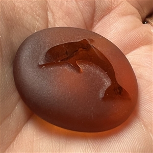 Amber glass button of a dolphin.