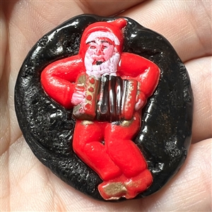 Resin button of man dressed as Santa playing an accordion.