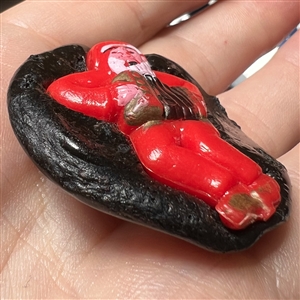 Resin button of man dressed as Santa playing an accordion.