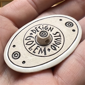 Oval ceramic button of morning glories by the Golem Studio.