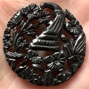 Casein button with open work of a cornucopia with flowers.