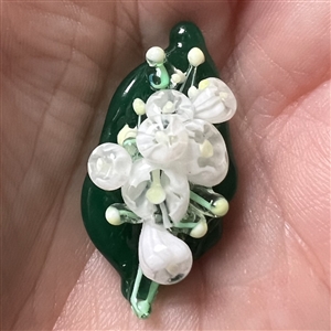 Mary Gaumond’s white lily of valley flowers on a leaf studio button.