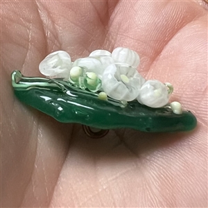 Mary Gaumond’s white lily of valley flowers on a leaf studio button.