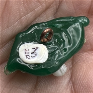 Mary Gaumond’s white lily of valley flowers on a leaf studio button.
