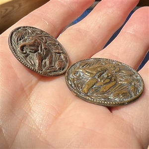 Two buttons of Teddy Roosevelt riding an elephant.