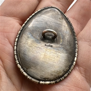 Reverse painted teardrop shaped button of woman gathering water.