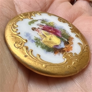 Lovely porcelain button of courting couple with rococo border.