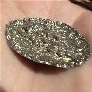 White metal “door knocker” button.