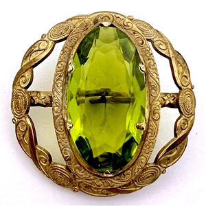 Gay 90s button with faceted peridot glass in gilded brass.